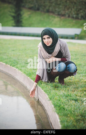 Porträt der jungen Frau tragen Hijab hocken am Park lake Stockfoto