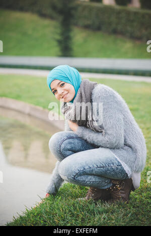 Porträt der jungen Frau trägt Hijab hocken neben dem Park-See Stockfoto