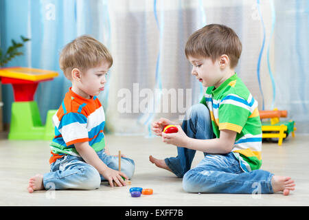 Zwei Kinder spielen mit Holzspielzeug auf dem Boden sitzend Stockfoto