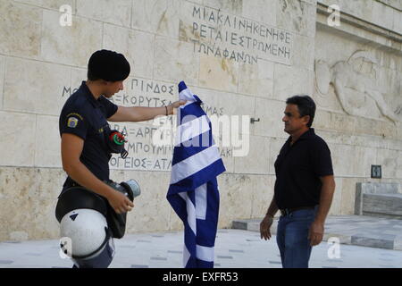 Athen, Griechenland. 13. Juli 2015. Ein Aufruhr Polizist kehrt die griechische Flagge in der Demonstrant. Griechen versammelten sich vor dem griechischen Parlament unter dem Banner der "verlassen wir dieses Europa". Sie forderten die Regierung auf die Forderungen der griechischen Gläubiger für weitere Sparmaßnahmen nicht nachgeben, sondern um die Eurozone zu verlassen. © Michael Debets/Pacific Press/Alamy Live-Nachrichten Stockfoto