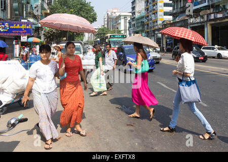 Yangon, Myanmar-Mai 5. 2014: Menschen, die die Straße überqueren. Menschen verwenden häufig Sonnenschirme sind Regenschirme, die Sonne zu schützen. Stockfoto