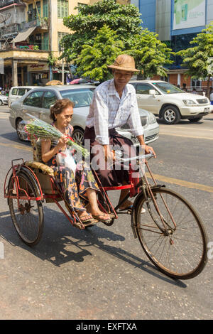 Yangon, Myanmar-Mai 5. 2014: eine Rikscha trägt einen Passagier zu ihrem Ziel. Diese Form des Transports ist nach wie vor verbreitet. Stockfoto