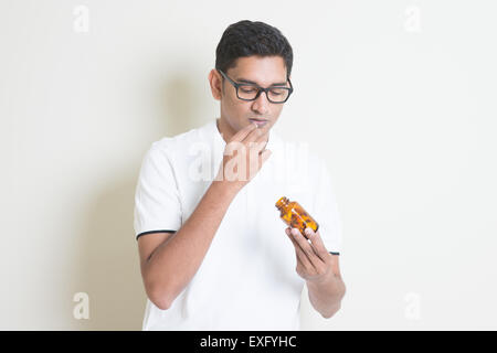 Krank Inder essen Medizin Pille. Asiatischen Mann auf einfarbigen Hintergrund mit Schatten und Kopie. Stockfoto
