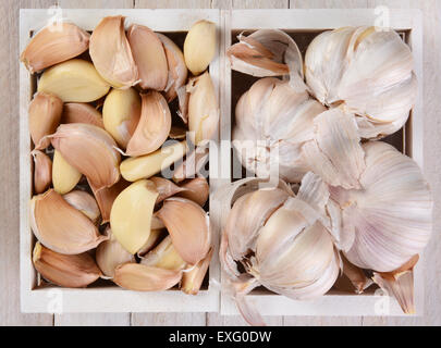 Erhöhte Ansicht von Knoblauch Zwiebeln und Knoblauchzehen in kleinen weißen Holzkisten. Stockfoto