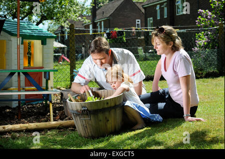 Eine Familie mit Tochter Pflanzen Samen in ihren Garten, Gloucestershire UK Stockfoto