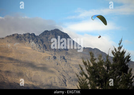 ein Tandem-Gleitschirm fliegt über Queenstown, Neuseeland mit der Remarkables im Hintergrund Stockfoto