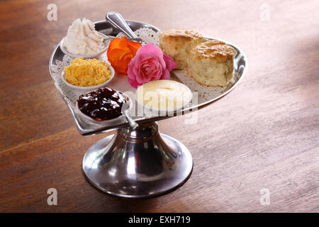 Köstliche Butter Gebäck auf einem Tablett Silber in Herzform mit Rosen Käse Sahne serviert und Marmelade auf einem Holztisch bewahrt. Stockfoto