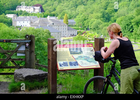 Weibliche Radfahrer Halt an der Infotafel über Cressbrook Mill auf dem Monsal Trail-Radweg in den Peak District, Großbritannien Stockfoto