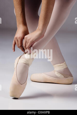 Weibliche Ballett-Tänzerin die Bänder ihrer Pointe Schuhe zu binden. Stockfoto