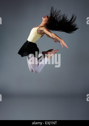 Schöne weibliche modernen jazz zeitgenössischer Stil Tänzerin auf einem grauen Hintergrund. Dancer ist barfuß und trägt ein gelbes Trikot, Bl Stockfoto