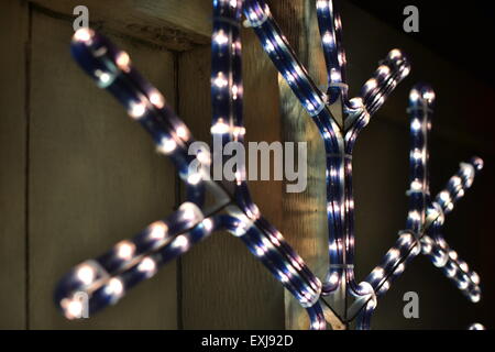 Dies ist eine leichte Weihnachtsdekoration außen ein Vorstadthaus. Die Lichter sind in der Form einer Schneeflocke an einem Zaun aufgehängt. Stockfoto