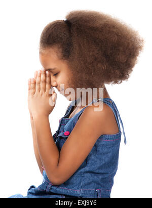 Entzückende niedliche afrikanischen Kindes mit Afro-Haar trägt ein Denim-Kleid. Das Mädchen Knien und beten. Stockfoto
