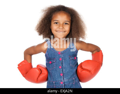 Entzückende niedliche afrikanischen Kindes mit Afro-Haar trägt ein Denim-Kleid. Das Mädchen ist das große rote Boxhandschuhe tragen. Stockfoto