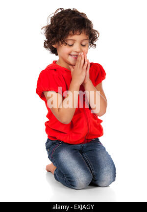 Entzückenden kleinen kaukasischen Kind mit dem lockigen Haar trägt ein leuchtend rotes Kapuzen Top und blaue Jeans. Das Mädchen Knien und beten. Stockfoto