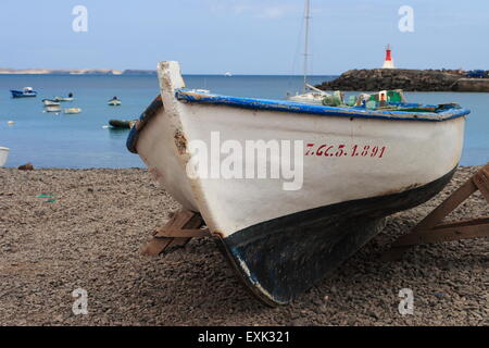 Mediterranen weißen Holz Fischerboot laufen auf einem steinigen Strand in Kanarische Inseln Spanien Stockfoto