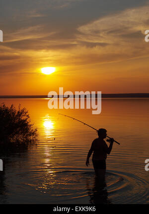 Fischer fängt Fisch Spinnen auf dem See bei Sonnenuntergang Stockfoto