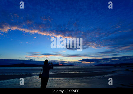 Lough Swilly, County Donegal, Irland. 14. Juli 2015. Irland Wetter: Sonnenuntergang über Lough Swilly County Donegal – 14. Juli 2015. Frau mit dem Fotografieren der untergehende Sonne über Lough Swilly in der Grafschaft Donegal. Bildnachweis: George Sweeney/Alamy Live News Live-Nachrichten Stockfoto