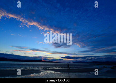 Lough Swilly, County Donegal, Irland. 14. Juli 2015. Irland Wetter: Sonnenuntergang über Lough Swilly County Donegal – 14. Juli 2015. Eine Frau zu Fuß auf Fahan Strand im County Donegal wie die Sonne geht über Lough Swilly. Bildnachweis: George Sweeney/Alamy Live-Nachrichten Stockfoto