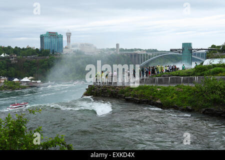 Touristen auf Luna Island blicken auf die amerikanischen Wasserfälle. Bridal Veil Falls Top Wappen im Vordergrund. Niagara Falls, New Yor Stockfoto