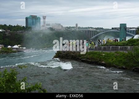 Touristen auf Luna Island blicken auf die amerikanischen Wasserfälle. Bridal Veil Falls Top Wappen im Vordergrund. Niagara Falls, New Yor Stockfoto