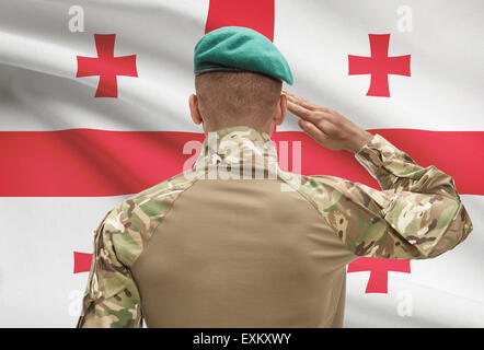 Dunkel-enthäutete Soldat im Hut vor Nationalflagge Reihe - Georgien Stockfoto