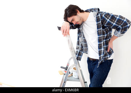 Ansicht eines jungen Mannes leiden während der Arbeit an einer Stehleiter Stockfoto