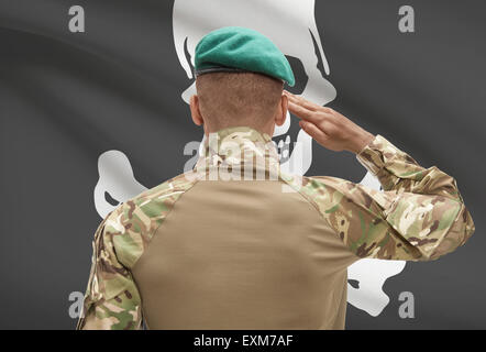 Dunkel-enthäutete Soldat im Hut vor Flagge Reihe - Jolly Roger Stockfoto