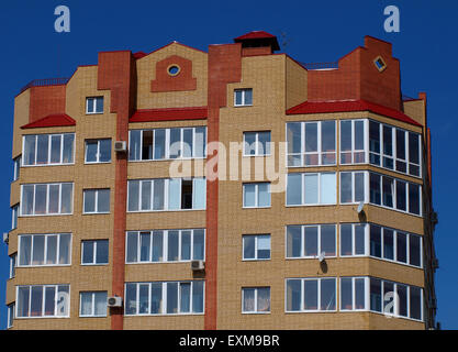 Die oberen Etagen des mehrstöckigen Gebäudes gegen den blauen Himmel ohne Wolken Stockfoto