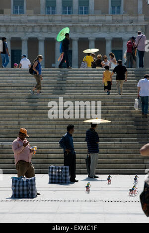 Migranten Straßenverkäufer verkaufen Regenschirme und Spielzeug sind gemeinsame Sicht auf Athen Alltag. Syntagma Platz, griechisches parlament. Griechenland. Stockfoto