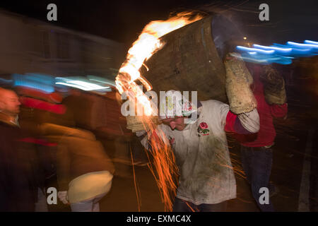 Zwischen brennenden Fass durchgeführt durch die Straße anlässlich Bonfire Night, 5 November, bei den Festspielen Tar Barrel schon St Mary, Devon, England Stockfoto