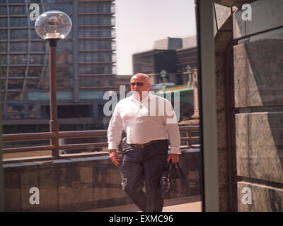 An einem Sommertag geht ein Mann entlang dem Nordufer der Themse in London Stockfoto
