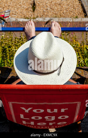 Ein Mann sitzt In einem Liegestuhl auf der Strandpromenade, Eastbourne, Sussex, UK Stockfoto