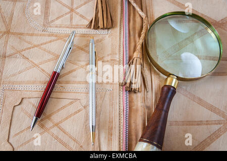 Lupe und zwei Stifte auf Ledermappe Stockfoto