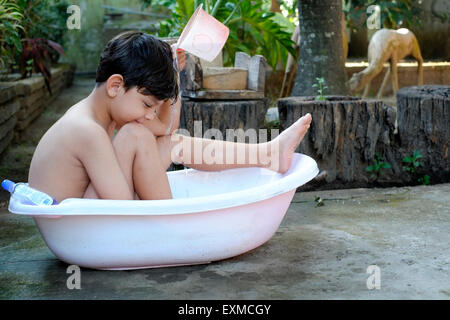 kleiner Junge Baden in eine Plastikschüssel in den Vorgarten in Java Indonesien Stockfoto