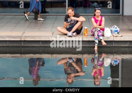 Paar Essen Pringles von Wasserspiel im Millennium Square in Bristol, England, UK Stockfoto