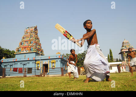 Jungen tragen weiße lungis spielen Spiel des Krickets vor Tempel am Navi Mumbai, Bombay, Maharashtra, Indien Stockfoto