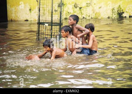 Straßenkinder genießen in den überfluteten Gewässern durch heftige Regenfälle in Chembur in Bombay jetzt Mumbai; Maharashtra; Indien Stockfoto