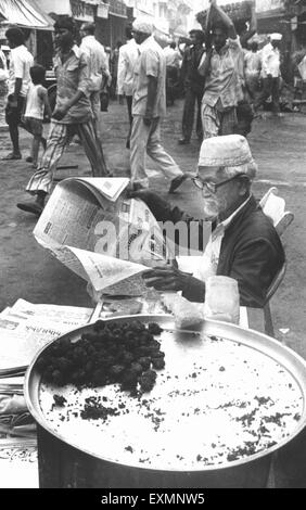 alte Mann liest Zeitung Streetfood Anbieter Mumbai Indien Stockfoto