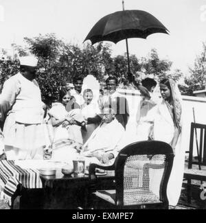 Mahatma Gandhi; sitzend auf einem Tisch; umgeben von Leuten an der Benares Hindu University; Varanasi; 1941; Indien nicht Herr Stockfoto