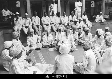 Dorfbewohner von Munagoli, die in traditionellen weißen Turbanen oder weißen Kappen gekleidet sind, versammeln sich im Hof des alten Hauses des Vermieters Munjaili, Morena, Madhya Pradesh, Indien, Asien Stockfoto