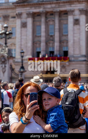 Ein Besucher braucht ein Selfie von sich selbst und Kind außerhalb der Buckingham Palace, London, England Stockfoto