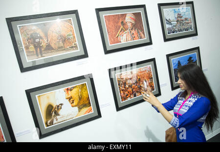 Berlin, Deutschland. 15. Juli 2015. Eine Frau nimmt ein Bild von den Fotografien von Deepak Tolange, ein Fotograf mit nepalesischen Wurzeln in seiner Ausstellung "Bilder aus den Ausläufern des Himalaya" in Berlin, Deutschland, 15. Juli 2015. Die Ausstellung, die 30 Fotografien umfasst ist, die Opfer des Erdbebens in Nepal zu unterstützen. Foto: Jörg CARSTENSEN/Dpa/Alamy Live News Stockfoto