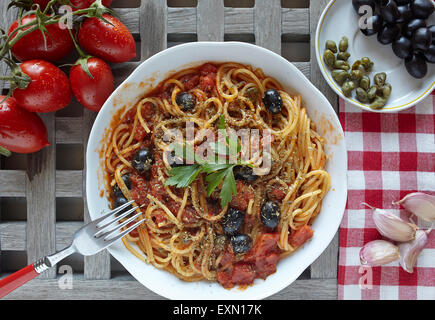 italienische Küche: Pasta mit Tomaten, Oliven und Kapern, genannt Puttanesca Stockfoto