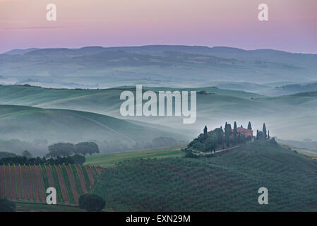 Nebligen Sonnenaufgang mit einem rosa Himmel und Nebel zwischen den toskanischen Hügeln über Agriturismo Podere il Belvedere Bauernhaus in der Valdorcia. Stockfoto