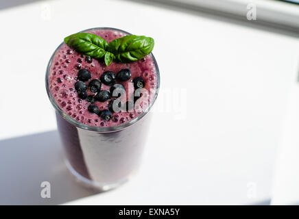 ein Glas Heidelbeer - Blätter Banane Smoothie, dekoriert mit frischen Heidelbeeren und Basilikum auf der Spitze eines Stockfoto