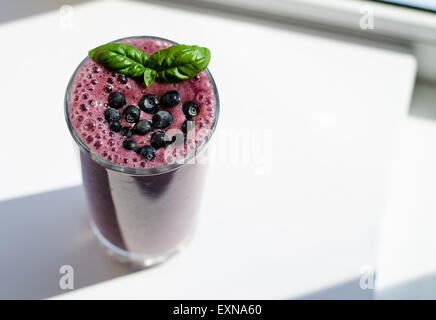 ein Glas Heidelbeer - Blätter Banane Smoothie, dekoriert mit frischen Heidelbeeren und Basilikum auf der Spitze eines Stockfoto