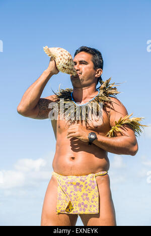 Ein lokaler polynesischen Mann mit einem Lendenschurz weht ein Conch Shell Horn in Bora Bora, Französisch-Polynesien. Stockfoto