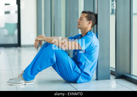 entspannte junge Ärztin, die auf dem Boden sitzend Stockfoto