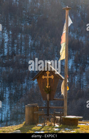 Kruzifix vor ein Chalet in italienischen Alpen im winter Stockfoto