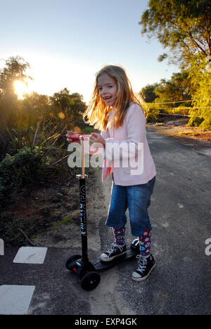 Junges Mädchen Lachen und Spaß auf ihrem Roller im Morgengrauen Stockfoto